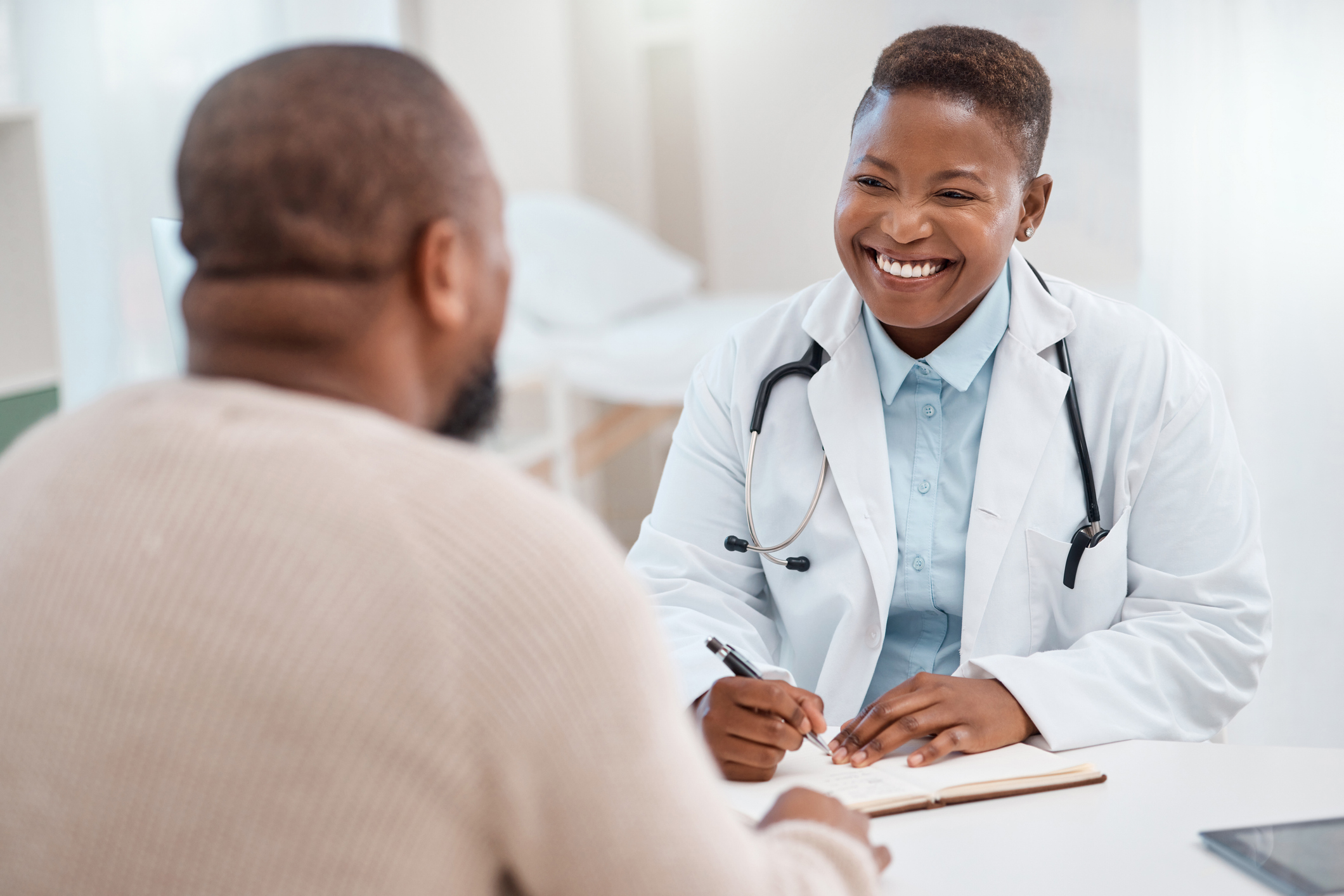 doctor writing notes during a consultation with a patient